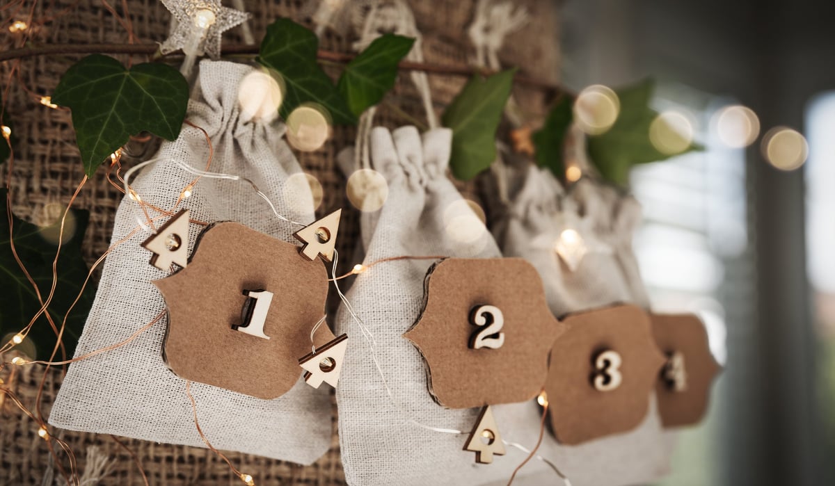 Advent calendar with little linen bags, string lights and pine branches