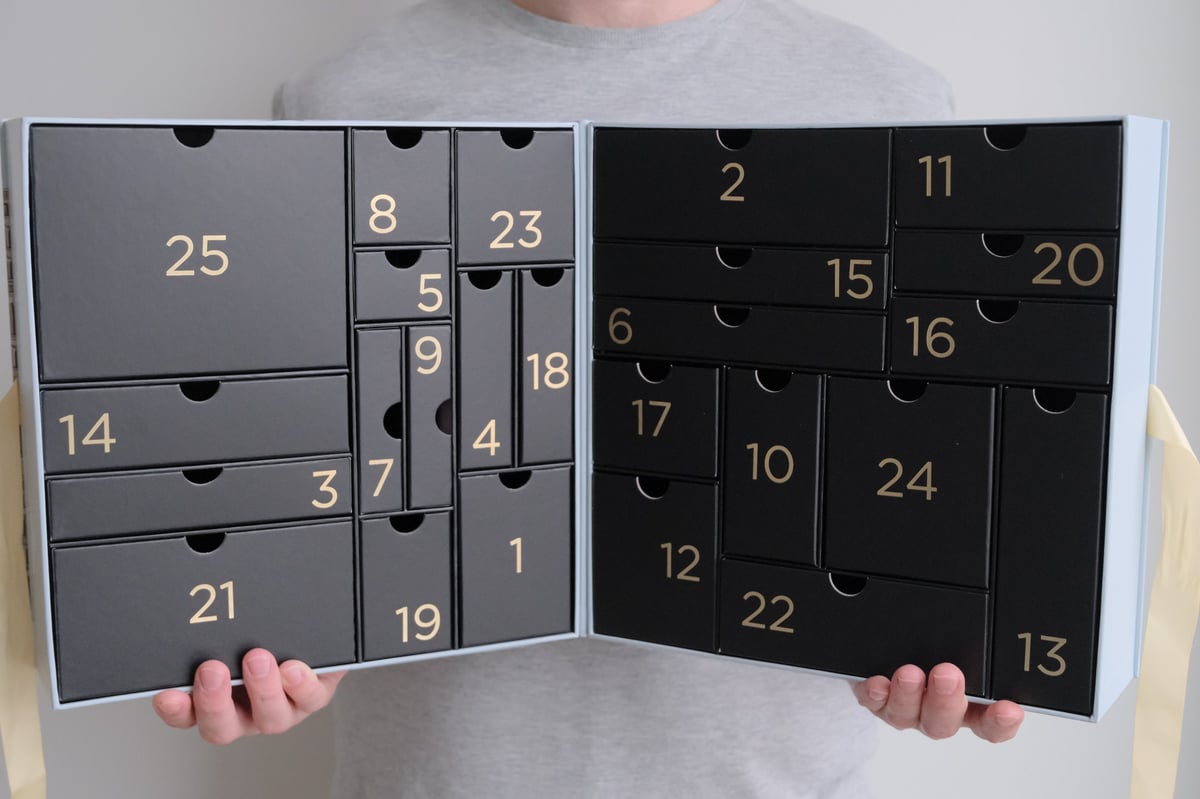 Hands opening a numbered advent calendar gift box with small drawers